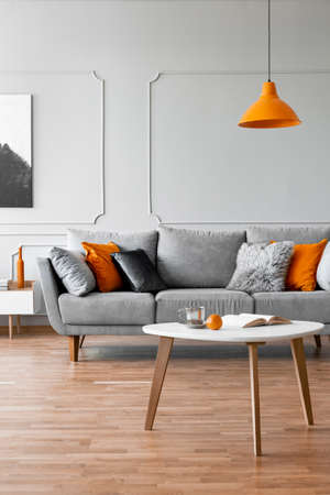 Living room with coffee table, grey comfortable sofa and orange lampの写真素材