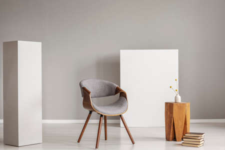 Stylish grey and wooden chair and coffee table between two white blocks of woodの写真素材
