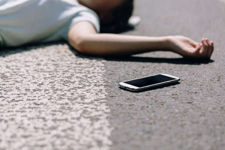 Smartphone on the pedestrian crossing after traffic accident with a personの写真素材