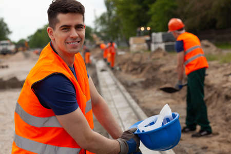 Handsome young road construction worker in orange safety jacketの写真素材