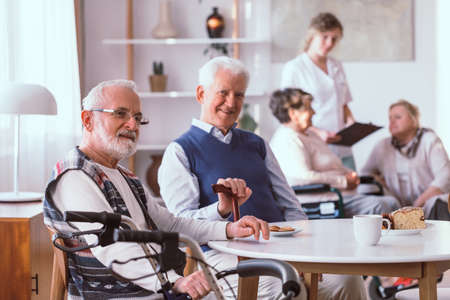 Disabled senior man sitting by the table in the retirement homeの写真素材