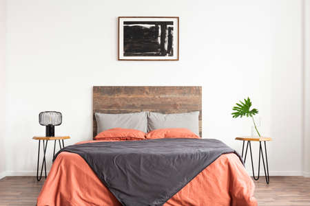 White bedroom with wooden headboard and coral and grey bedsheetsの写真素材
