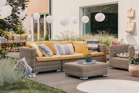 Real photo of a rattan garden furniture set with lamps and table in the backgroundの写真素材