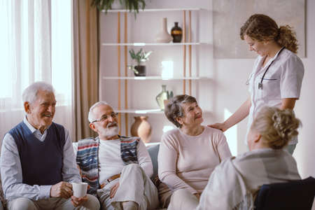 Smiling seniors talking with nurse in the retirement home