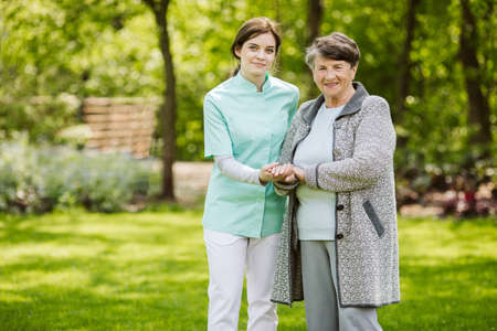 Young nurse with elder woman in the gardenの写真素材