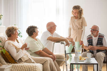 Senior patients with helpful young nurse at nursing homeの写真素材