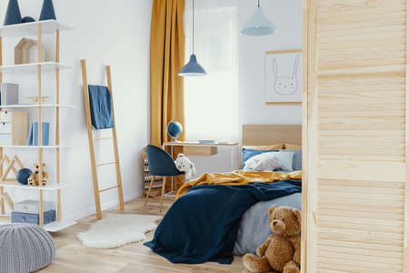 Messy kid's bedroom with toys and wooden furniture real photoの写真素材