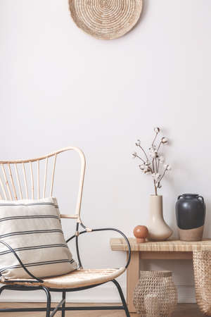 vertical view of wicker chair with pillow ext to table with ans basked made of strawの写真素材