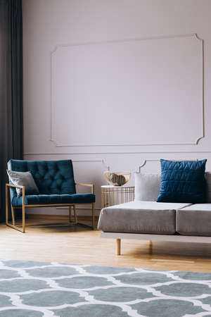 Petrol blue velvet armchair in stylish living room interior in trendy apartment