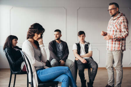 Depressed woman isolating herself from her psychotherapy group in mental hospitalの写真素材