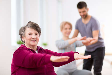 Senior lady exercising during group physiotherapy at rehabilitation centerの写真素材