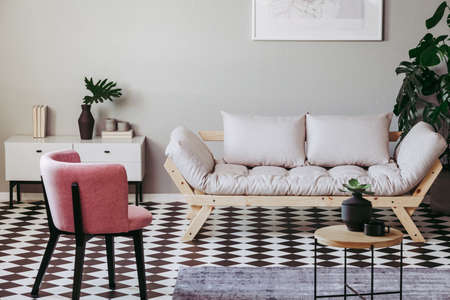 Pastel pink chair in beige and grey living room interiorの写真素材