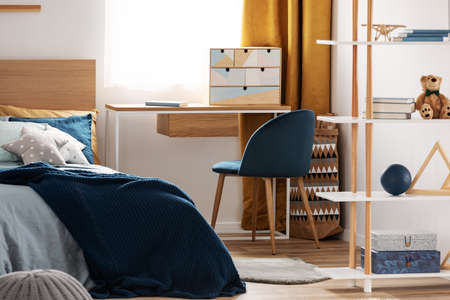 Workspace with desk and chair in elegant teenager's room with blue and orange designの写真素材