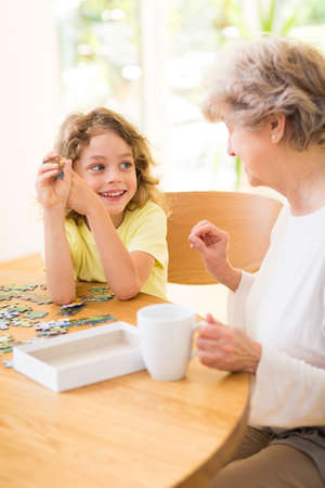 Boy and his grandmother assembling the puzzle togetherの写真素材