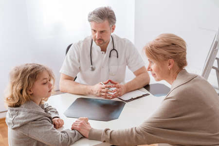 Mom and cute sick son in front of the handsome pediatrician's deskの写真素材