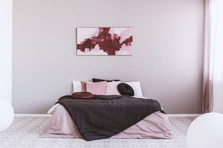 Abstract white and burgundy painting on the wall of stylish bedroom interior with king size bedの写真素材