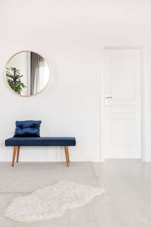 Elegant round mirror above velvet bench in white waiting room interiorの写真素材