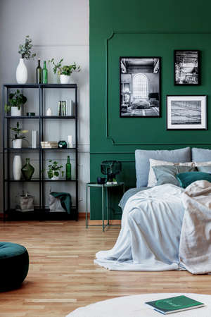 Gallery of black and white poster on green wall behind king size bed with pillows and blanketの写真素材