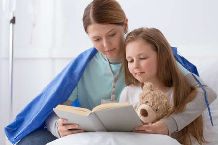 Young blond girl and a volunteer reading herの写真素材