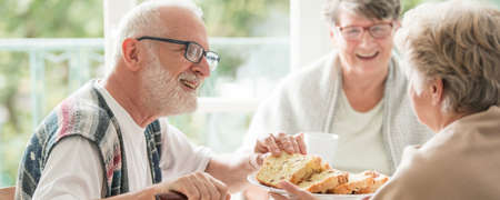 Happy seniors sharing cake during coffee meeting at nursing homeの写真素材