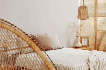 Wooden screen in white bedroom interior with wooden nightstandの写真素材
