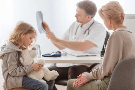 Mom and cute sick son in front of the handsome pediatrician's deskの写真素材