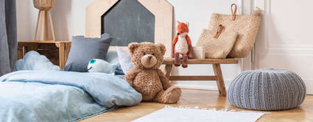 Little boys bedroom with toys, grey pouf and bed with light blue sheets, real photoの写真素材