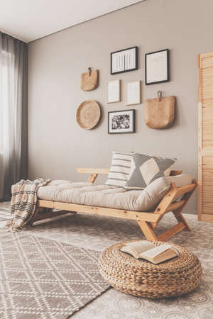 Open book on wicker pouf in bright living room interiorの写真素材