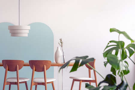 White lamp above long wooden table with vases and stylish chairsの写真素材