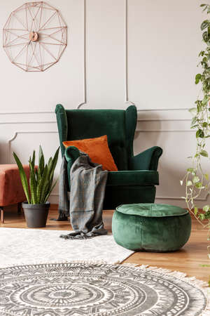 Comfortable emerald green armchair with orange pillow in fashionable living room interiorの写真素材