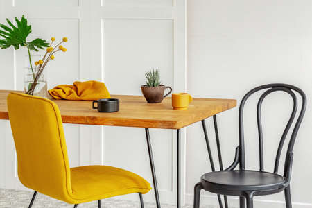 Yellow and black chair at wooden kitchen table with coffee cupsの写真素材