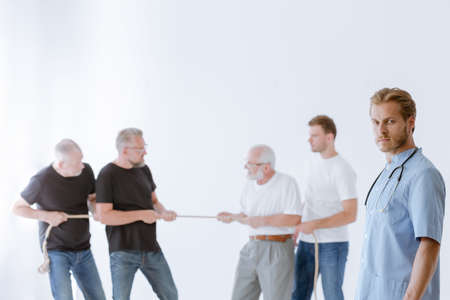 Young doctor and the group of men pulling the ropeの写真素材
