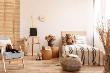 Teddy bear on single wooden bed in natural kid's bedroomの写真素材