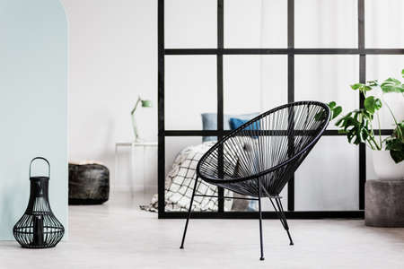 Back pouf next to bedside table with lamp in elegant bedroom interiorの写真素材