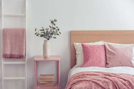 Pastel pink pillow and blanket on single wooden bed with white bedding in scandinavian bedroom interiorの写真素材