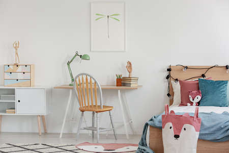 Bright bedroom interior with single bed with turquoise blanket on white bedding and colorful pillows and toyの写真素材