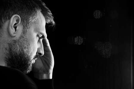 Copy space on black background next to face of worried man with problem