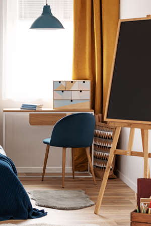 Workspace with desk and chair in elegant teenager's room with blue and orange designの写真素材