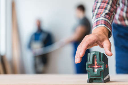 Close-up of builder's hand reaching for a laser levelの写真素材