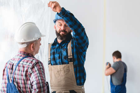 Builders in hardhats spreading protective foil around the roomの写真素材