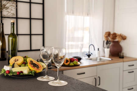 Wine glasses and fruits on kitchen counter in bright kitchen interiorの写真素材