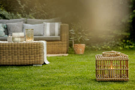 Modern rattan lamp and wicker sofa in a background in the gardenの写真素材