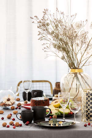 Common dining room table with food, fruits, cake and flowers in vase