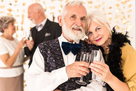 Cute elegant senior couple toasting with champagne during New Year's Eveの写真素材