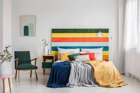 Retro armchair in modern bedroom interior with rainbow colored headboardの写真素材