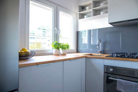 Herbs and lemons on wooden counter of small kitchen with white cupboards