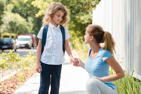 Young mom saying goodbye to her son before schoolの写真素材