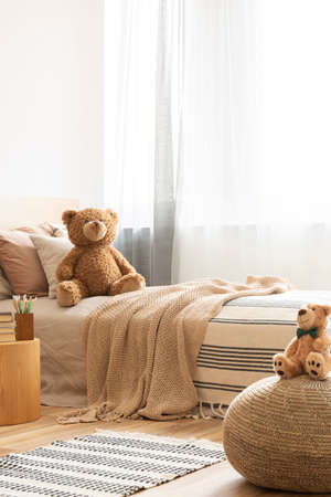 Cute teddy bear on single bed in bright kid's roomの写真素材