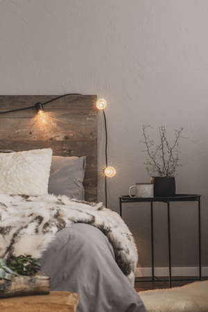 Warm duvet on comfortable bed with rustic headboard with lightsの写真素材