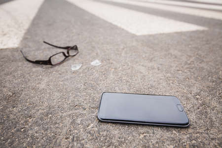 Close-up of the phone and broken glasses on the streetの写真素材